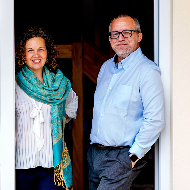 Jacqs and John standing in a doorway with the sun out